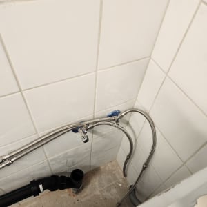 צנרת מים וחיבורים בקיר אריחים לבנים