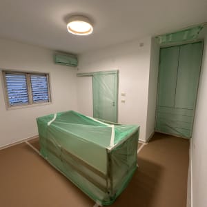 חדר עם רהיטים מכוסים בניילון ירוק לקראת צביעה