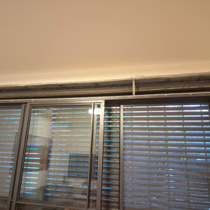 תריסים אפורים סגורים על חלון זכוכית גדול