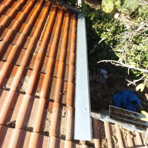 רעפים חומים על גג עם מרזב מתכת אפור