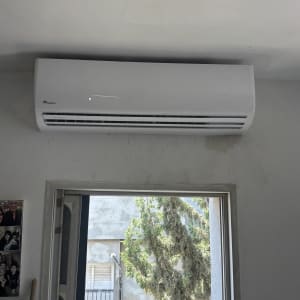 מזגן מותקן על קיר ליד חלון פתוח