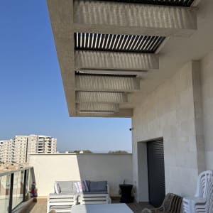 פרגולה מאלומיניום במרפסת עם שולחן וכיסאות