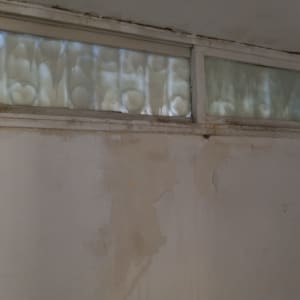 חלון עם זכוכית מטושטשת וקיר עם קילופי צבע