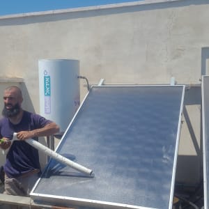 אדם מתקין דוד שמש על גג עם צינור ביד