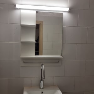 כיור עם מראה ותאורה בחדר אמבטיה