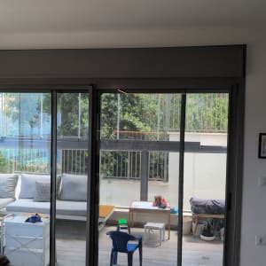 תריסים על חלון זכוכית בסלון עם נוף לחצר