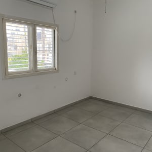 חדר ריק עם רצפה נקייה ותריסים סגורים