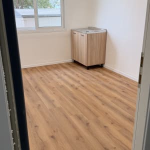 רצפת פרקט בחדר עם חלון וארון קטן