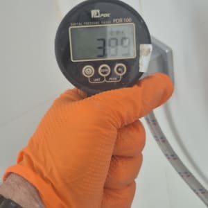 מד לחץ דיגיטלי מוחזק על ידי יד בכפפה כתומה