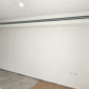 קיר לבן צבוע עם רצפת אריחים אפורה