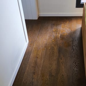 רצפת עץ כהה ליד קיר עם שקע חשמל