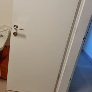 דלת לבנה עם ידית מתכת על רצפת עץ