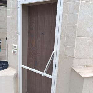 דלת אלומיניום עם מסגרת לבנה וקיר אבן