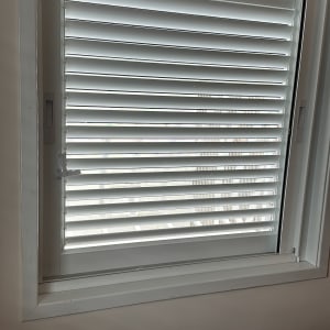 תריסים לבנים מותקנים בחלון