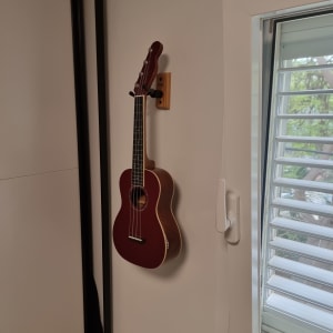 גיטרה תלויה על קיר ליד חלון עם תריסים
