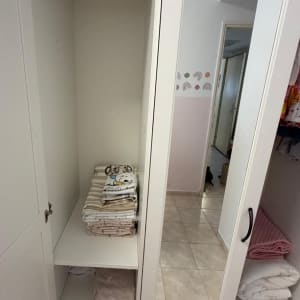 ארון בגדים לבן פתוח ומסודר עם מצעים ושמיכות מקופלות במדפים
