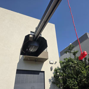 מנוע שער חשמלי עם חוט אדום תלוי ליד בניין