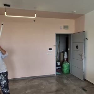 אדם צובע קיר בחדר עם רולר צבע
