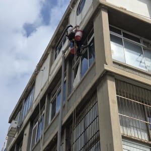 אדם עובד בגובה על בניין עם ציוד טיפוס