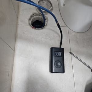 מכשיר בדיקת נזילות עם צינור כחול על רצפת חדר אמבטיה