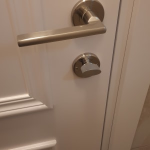 ידית דלת מתכתית על דלת לבנה