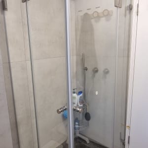 מקלחון זכוכית עם ראש מקלחת ומדף מוצרים