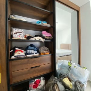 ארון בגדים עם מדפים מלאים בבגדים מקופלים ושקיות בגדים על הרצפה