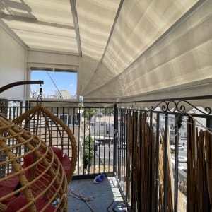 מרפסת עם סוכך לבן תלוי מעל, כיסאות תלויים