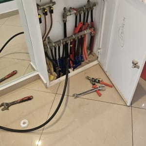 ארון פתוח עם צינורות וכלי עבודה על הרצפה