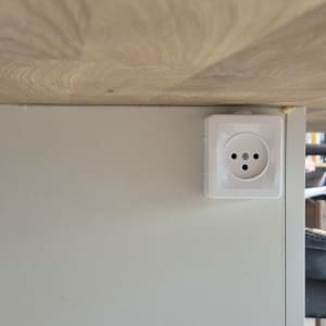 שקע חשמל מותקן על קיר מתחת לשולחן עץ