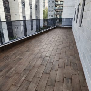 מרפסת עם רצפת עץ נקייה ומבנים ברקע