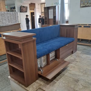 ספסל עץ עם מדפים וכרית כחולה בבית כנסת