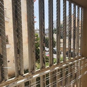 רשת מתכת על חלון למניעת כניסת יונים
