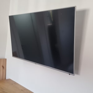 טלוויזיה מותקנת על קיר עם שלט על השידה