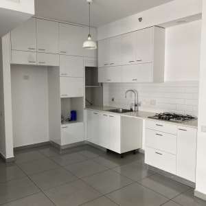 מטבח נקי עם כיור וברז, ארונות לבנים