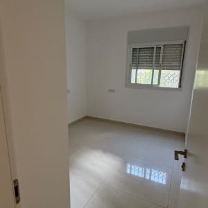 חדר ריק עם רצפת קרמיקה וחלון עם תריסים