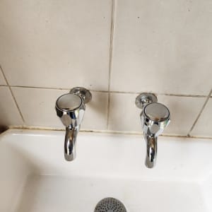 ברזים כפולים מעל כיור לבן עם ניקוז