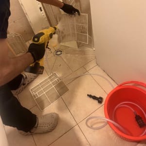 אדם מנקה מסנן של מזגן עם מכשיר שטיפה