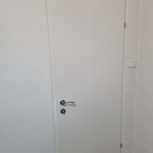 דלת לבנה עם ידית מתכת על קיר לבן