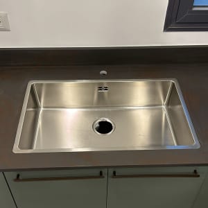 כיור נירוסטה על משטח שיש כהה במטבח