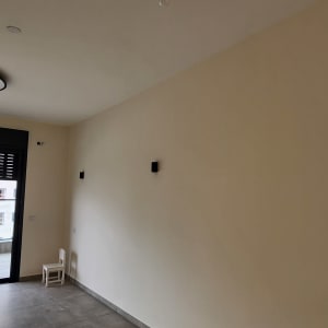 קיר צבוע עם חלון גדול וכיסא קטן