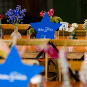 שולחן מעוצב עם פרחים ושלט Make-A-Wish