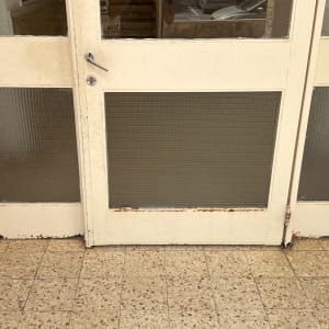 דלת זכוכית עם ידית מתכת ורצפת אריחים