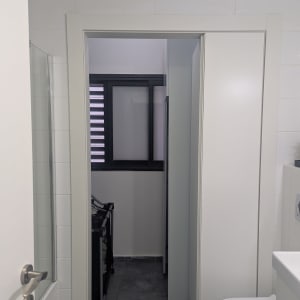 דלת לבנה בחדר אמבטיה עם חלון קטן