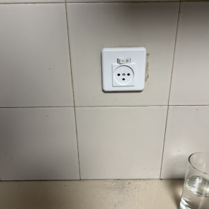 שקע חשמל עם מתג על קיר אריחים לבנים