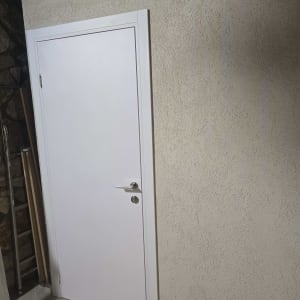 דלת לבנה מותקנת בקיר עם ידית כסופה
