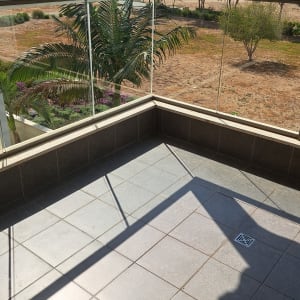 מרפסת נקייה עם ריצוף גרניט פורצלן ומעקה זכוכית שקוף