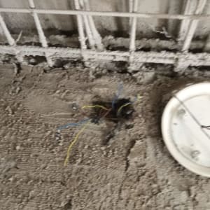 חוטי חשמל חשופים על רצפה ליד מכסה עגול