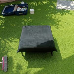 כרית שחורה על דשא סינתטי עם כלי ניקוי