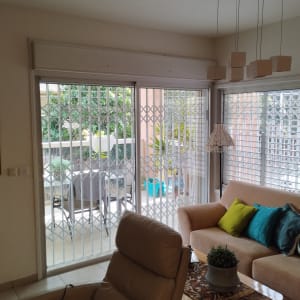 תריסים לבנים מתקפלים על חלונות זכוכית